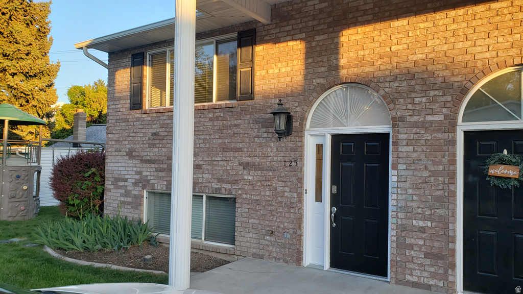 Doorway to property with brick siding and covered porch