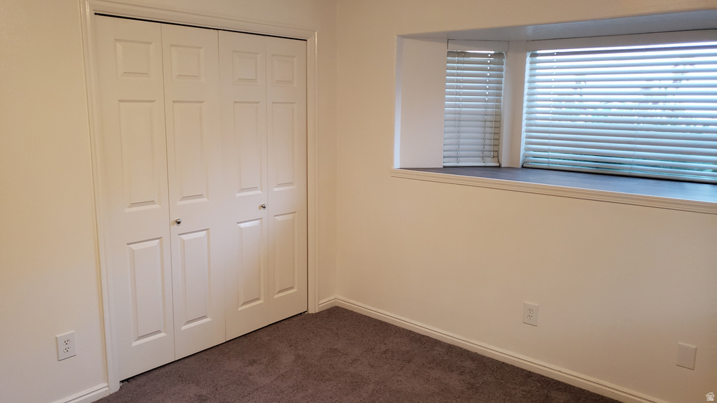 Unfurnished bedroom with dark colored carpet and a closet