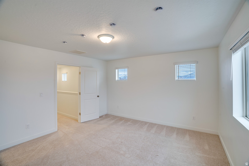 Unfurnished room featuring light colored carpet and a textured ceiling