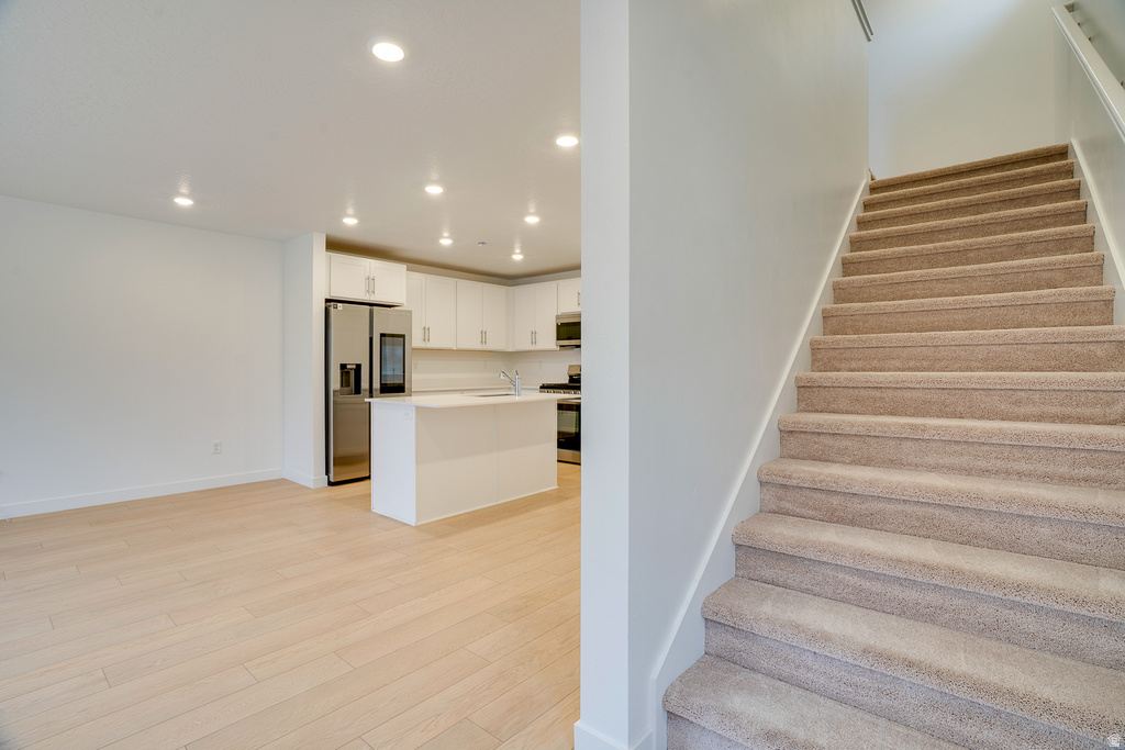 Stairs featuring recessed lighting and wood finished floors