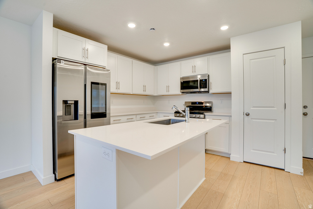 Kitchen with stainless steel appliances, white cabinets, a kitchen island with sink, and recessed lighting