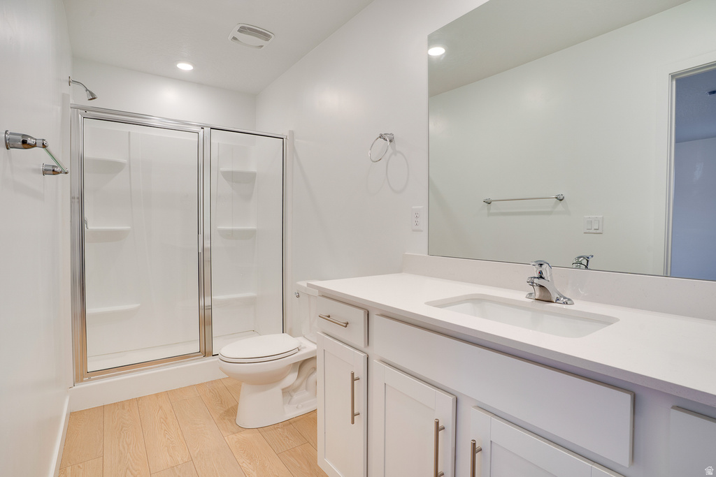 Bathroom featuring a shower stall, vanity, light wood-style floors, and recessed lighting