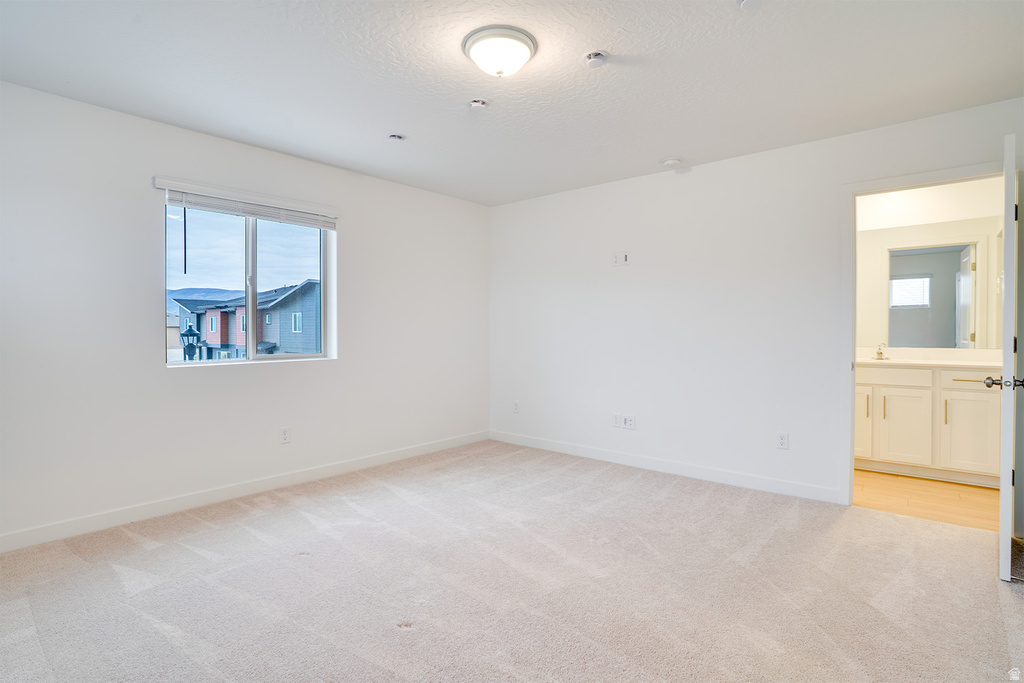 Empty room featuring light colored carpet and a textured ceiling