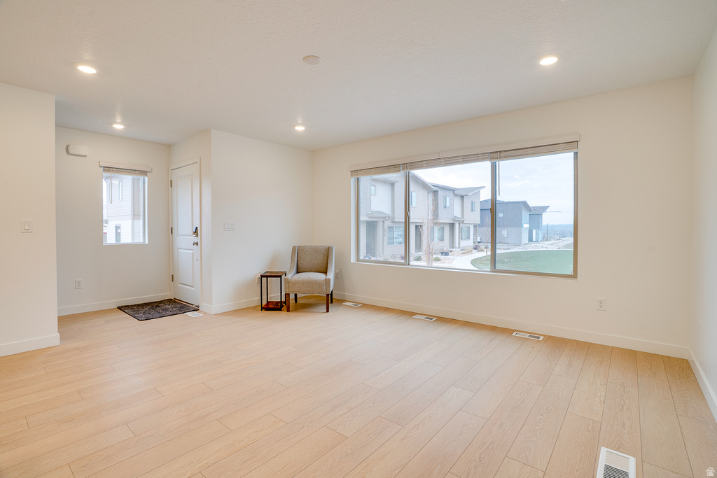 Living area featuring light wood-type flooring, healthy amount of natural light, and recessed lighting