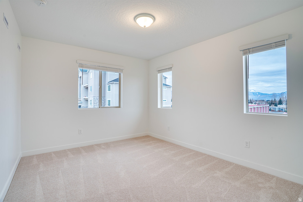 Empty room with light carpet and baseboards