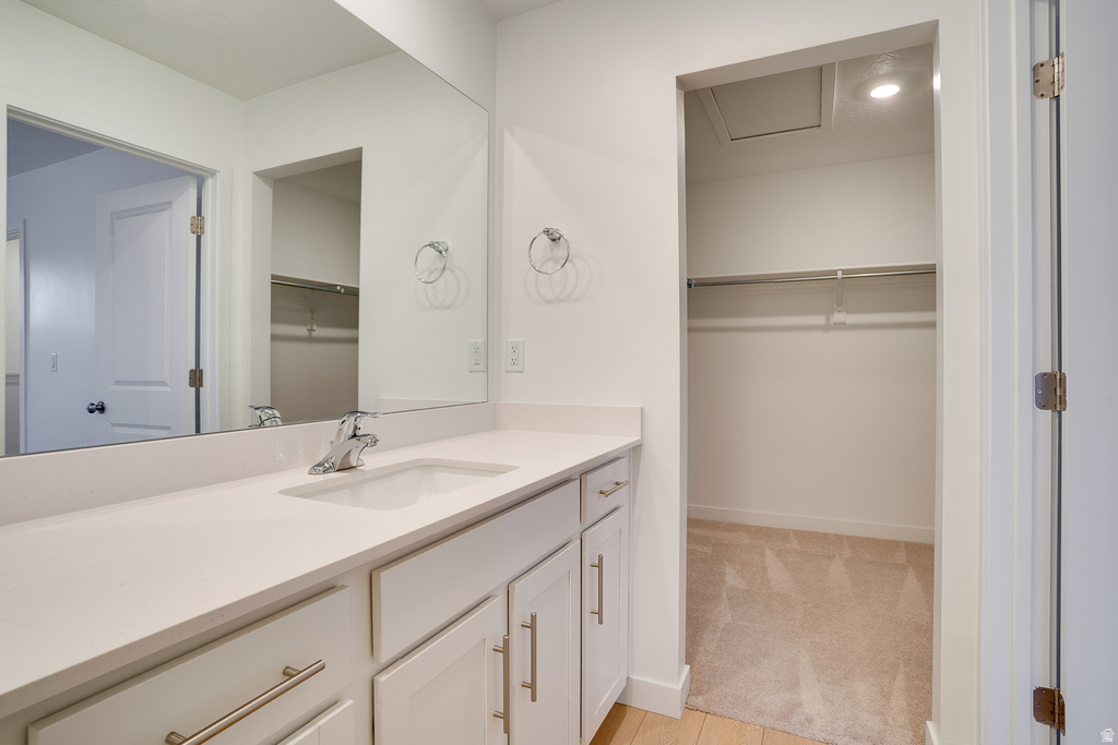 Bathroom featuring a walk in closet, vanity, and light colored carpet