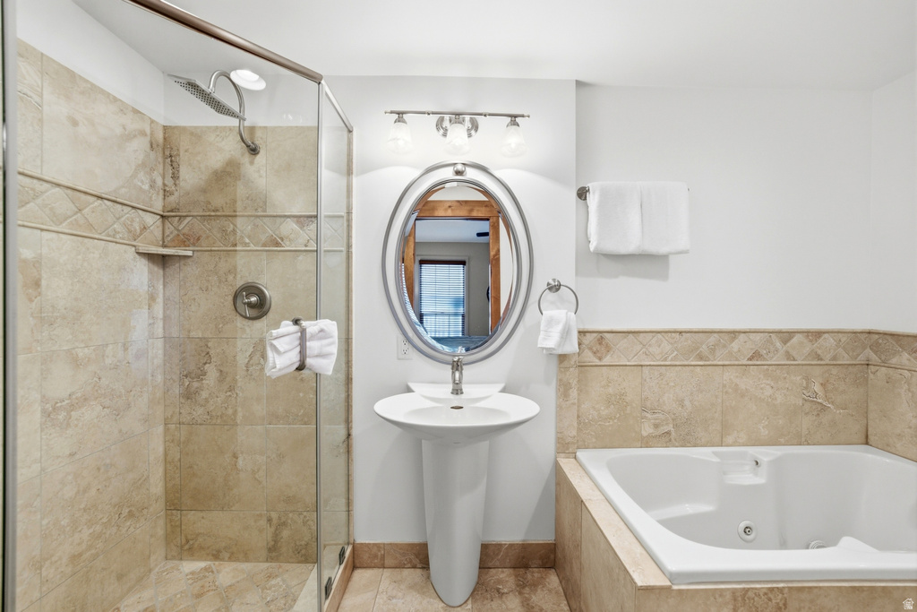 Bathroom featuring a glass-enclosed shower, a built-in tub, and a pedestal sink