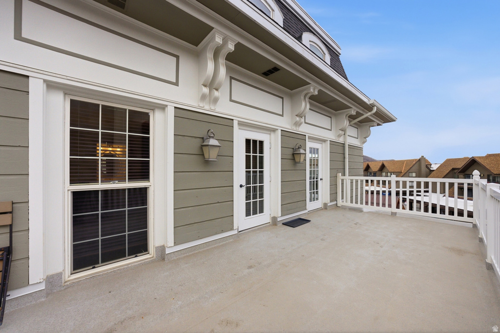 Expansive outdoor deck featuring a concrete surface, white railing, and exterior wall lanterns