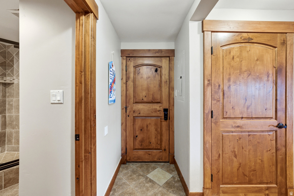 Hallway featuring wood-finish doors with arched panels and dark hardware