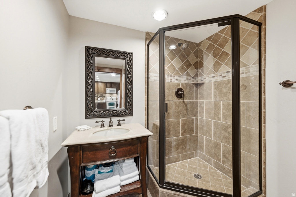 Corner glass-enclosed shower featuring tiled walls and flooring with decorative mosaic accent