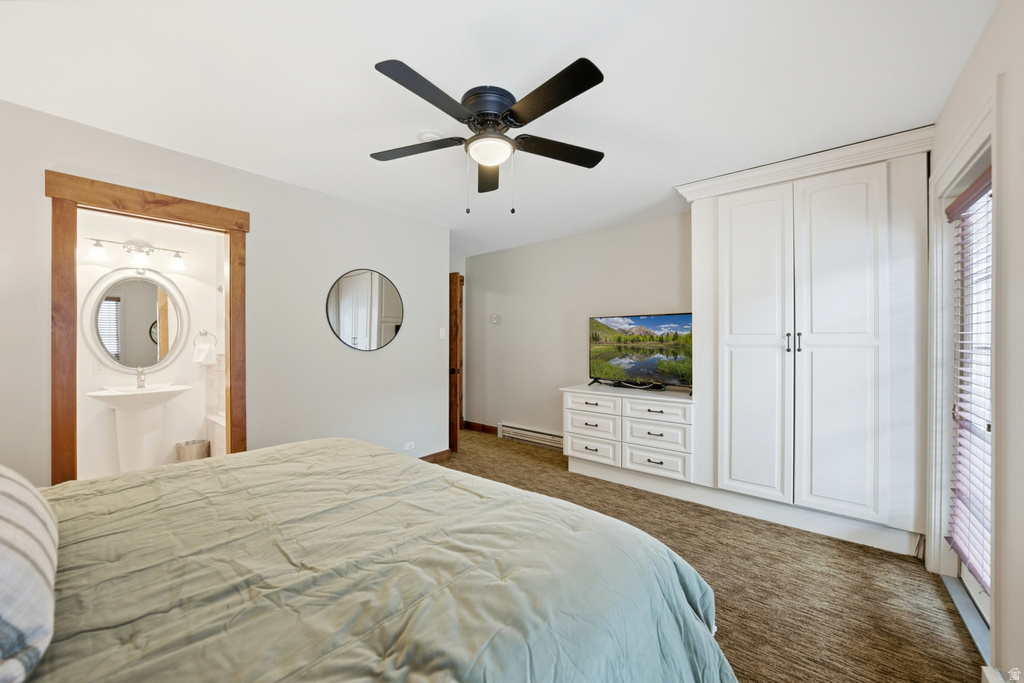 Bedroom featuring built-in cabinetry, integrated media console, and an attached three-quarter bathroom with a pedestal sink and circular mirror