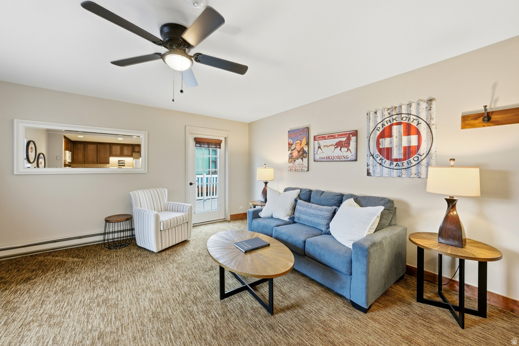 Living area featuring a ceiling fan with integrated lighting, a full-lite exterior door, and a wall-mounted mirror reflecting kitchen cabinetry