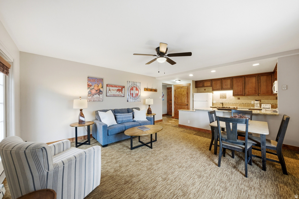 Open-concept living area featuring a kitchen with wood cabinetry, a dining area with seating for four, and a ceiling fan