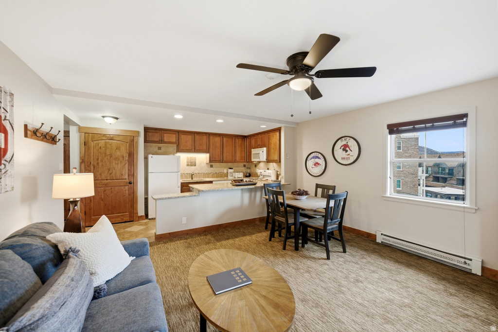 Open-concept living space featuring a kitchen with wood cabinetry, a dining area, and a living area with carpeted flooring