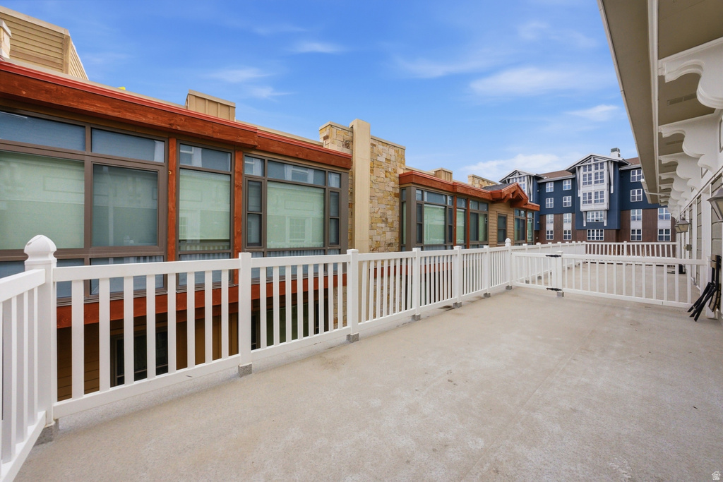 Expansive outdoor deck featuring a white railing system, concrete flooring, and architectural details including stone and wood-finish accents