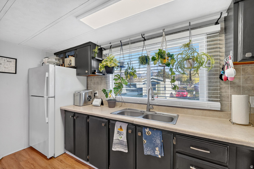 Kitchen with freestanding refrigerator, light countertops, tasteful backsplash, and light wood-style flooring