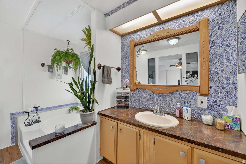 Bathroom with a bath, vanity, and tasteful backsplash