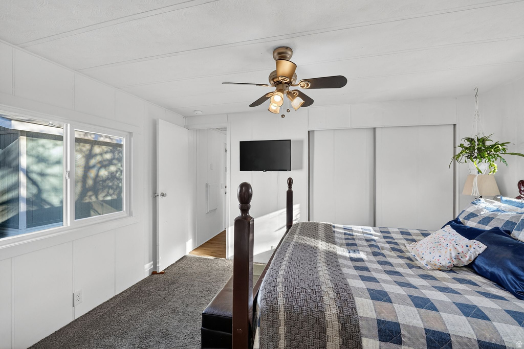 Carpeted bedroom featuring a decorative wall, a closet, and a ceiling fan