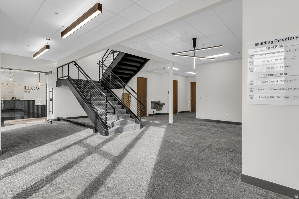 Below grade area with carpet flooring, a paneled ceiling, and stairs