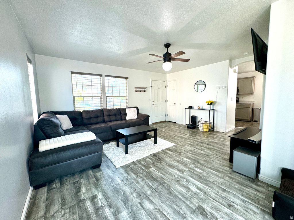 Living area with a textured ceiling, wood finished floors, and a ceiling fan