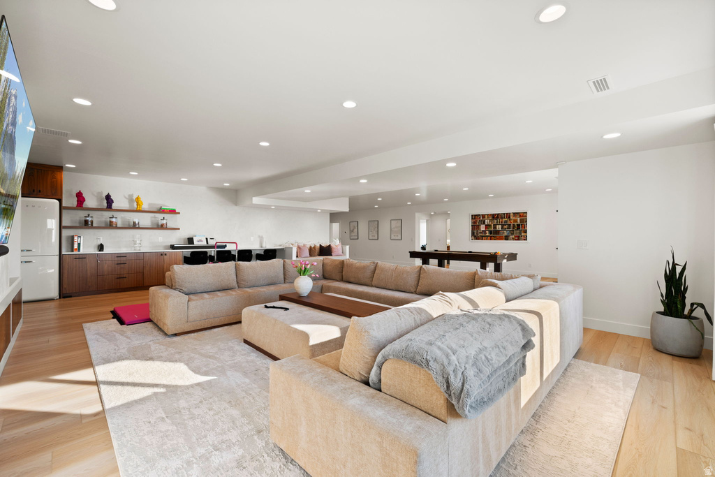 Living room featuring wet bar, light wood-style floors, and recessed lighting