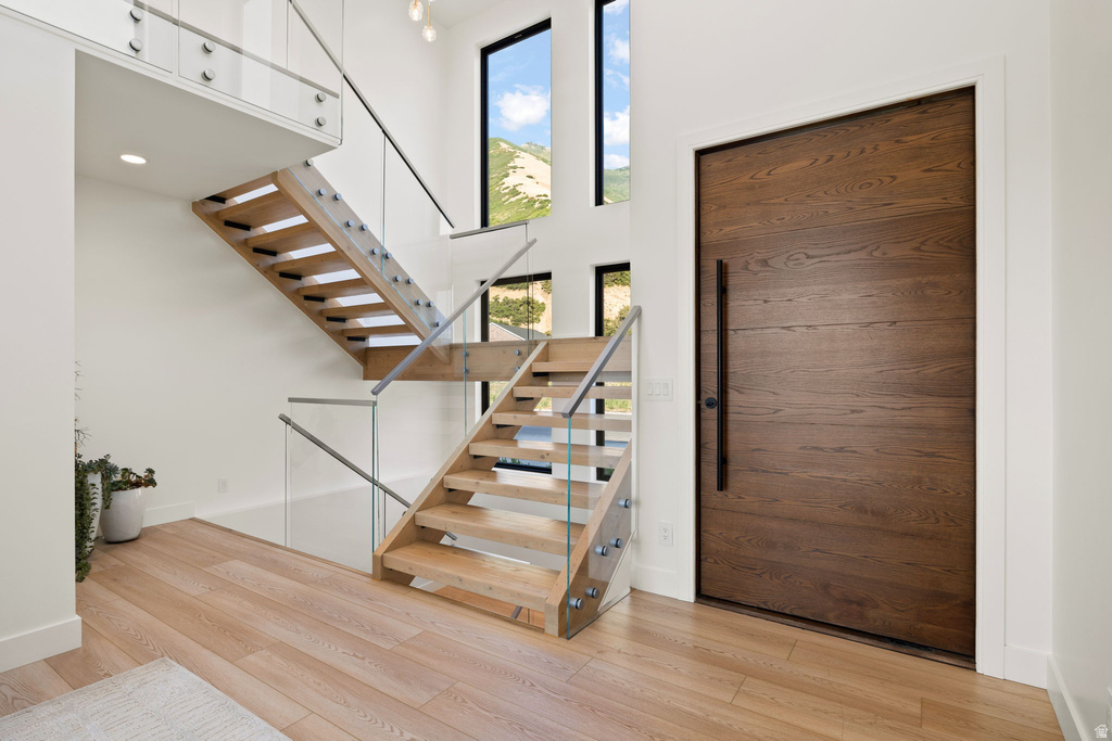 Entrance foyer with stairs, a high ceiling, and light wood-style floors