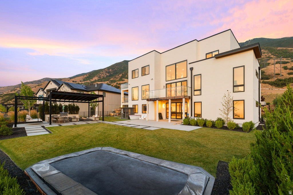 Rear view of house featuring a patio, a yard, stucco siding, and a mountain view