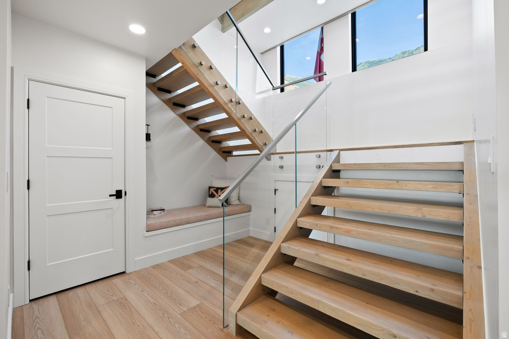 Staircase with wood finished floors and recessed lighting