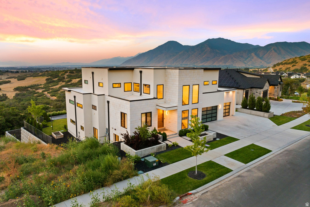Contemporary home with concrete driveway, stucco siding, a garage, and a mountain view