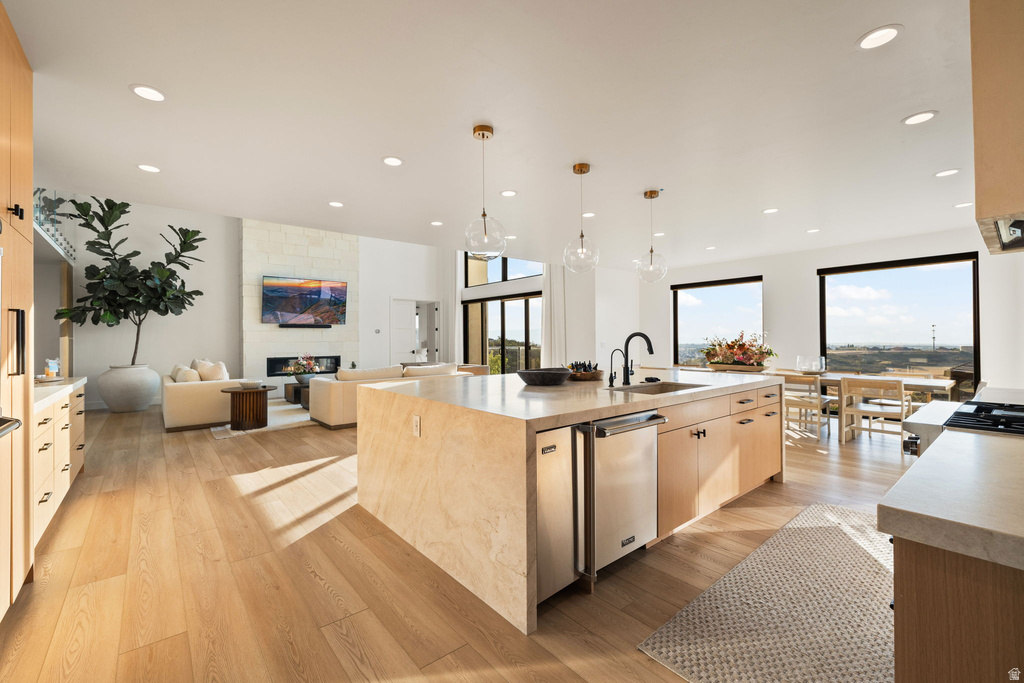 Kitchen featuring open floor plan, light wood-type flooring, a center island with sink, hanging light fixtures, and recessed lighting