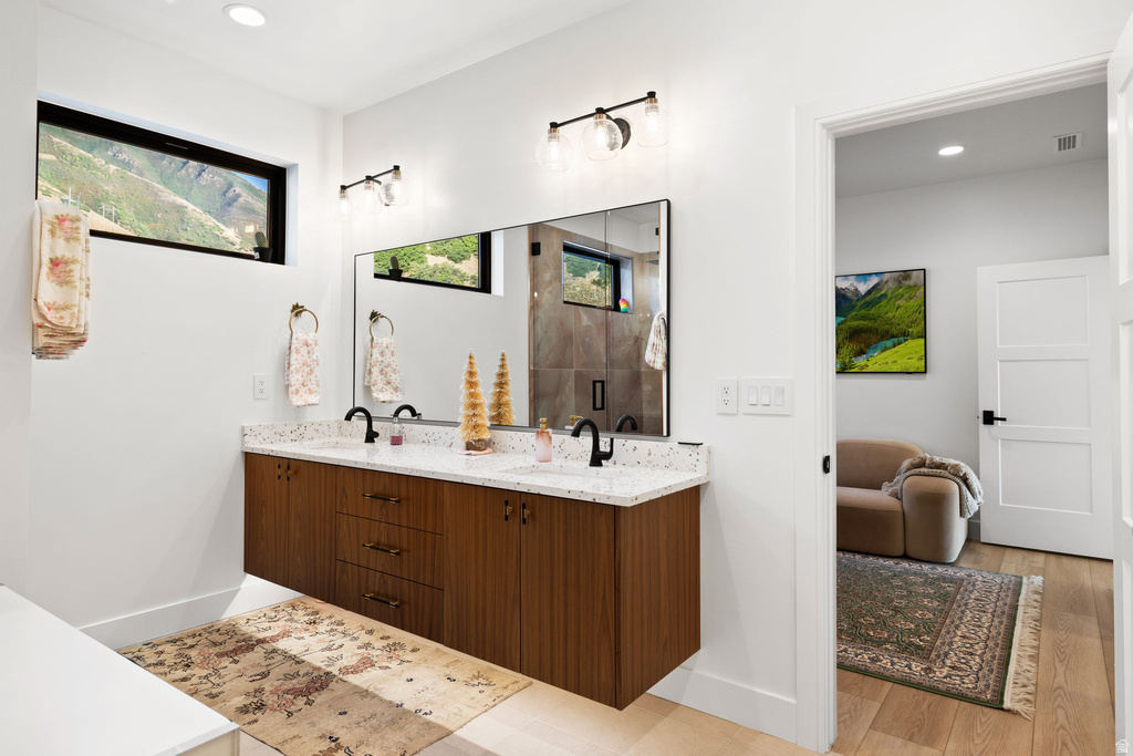 Full bath featuring double vanity, recessed lighting, a shower stall, and light wood-style flooring