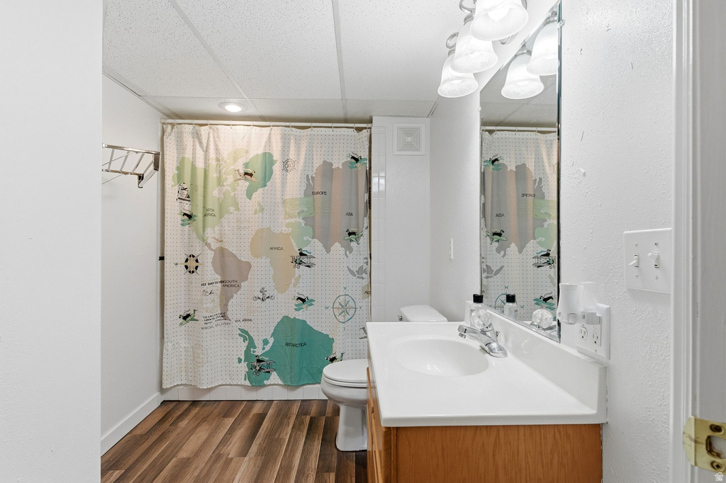Full bath featuring a drop ceiling, curtained shower, vanity, and dark wood finished floors