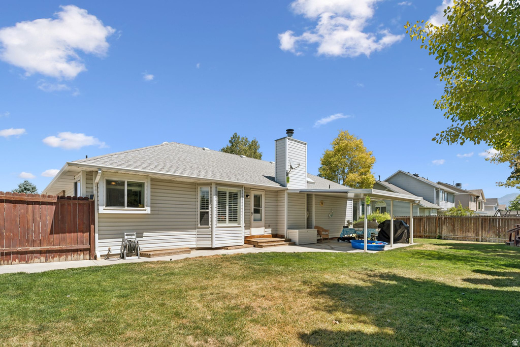 Back of house featuring a patio, roof with shingles, a fenced backyard, a chimney, and entry steps