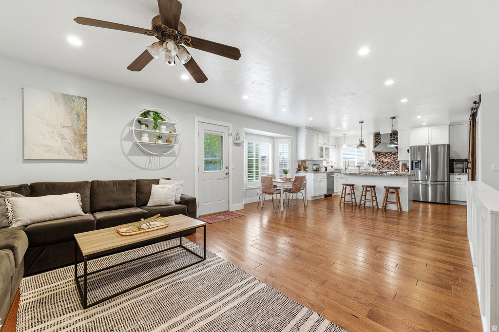 Living area with light wood finished floors, recessed lighting, and a ceiling fan