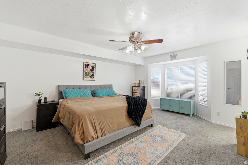 Carpeted bedroom with a ceiling fan and a textured ceiling