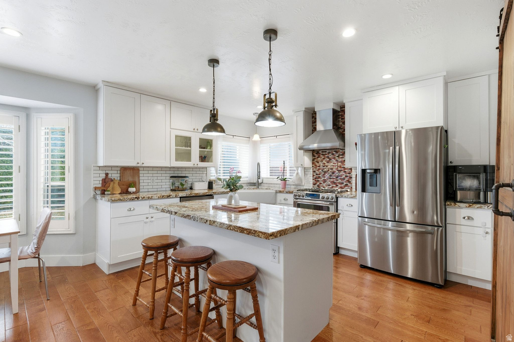 Kitchen with stainless steel appliances, backsplash, a kitchen breakfast bar, white cabinets, and recessed lighting