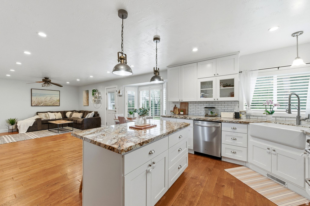 Kitchen with white cabinetry, light stone counters, open floor plan, a center island, and light wood-type flooring