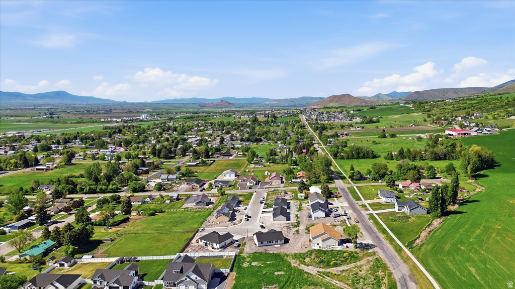 Expansive rural landscape featuring a mix of developed residential areas and open green fields, framed by distant mountains under a clear sky