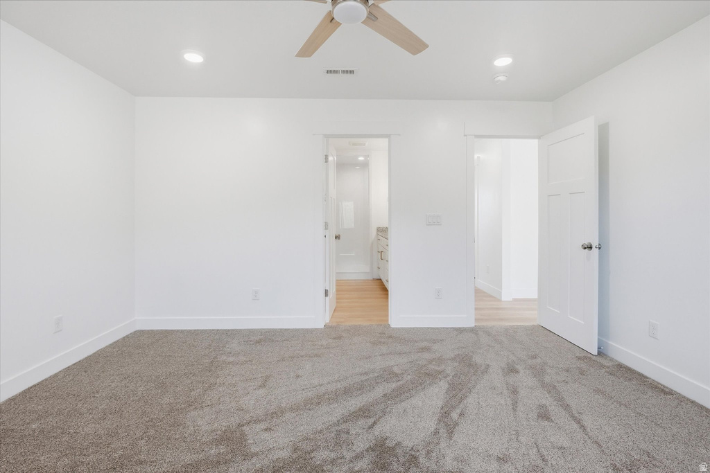 Spacious room featuring neutral carpeting, white walls, recessed lighting, and a ceiling fan