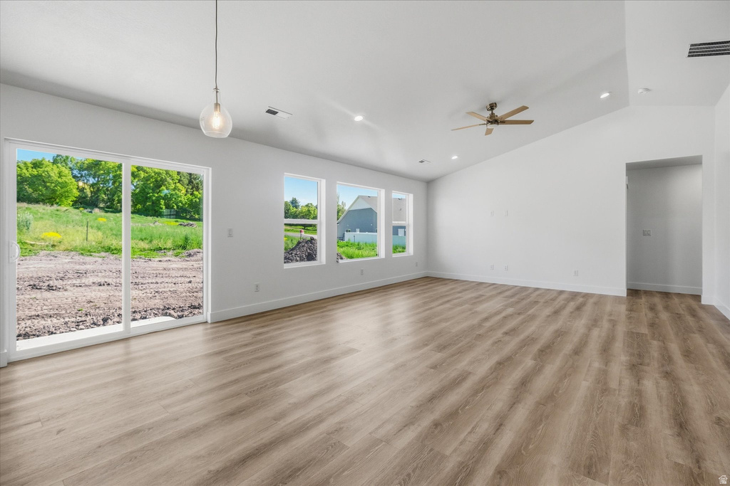 Open concept living space featuring light wood-finish flooring, a vaulted ceiling, and multiple windows