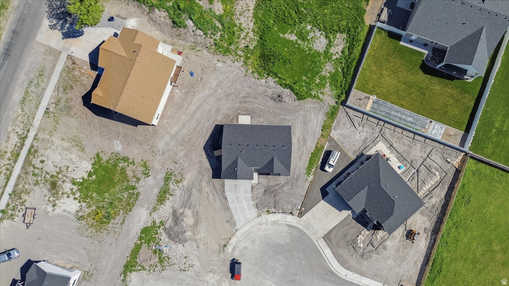 New construction residence with an asphalt shingle roof, concrete driveway, and ample surrounding undeveloped land