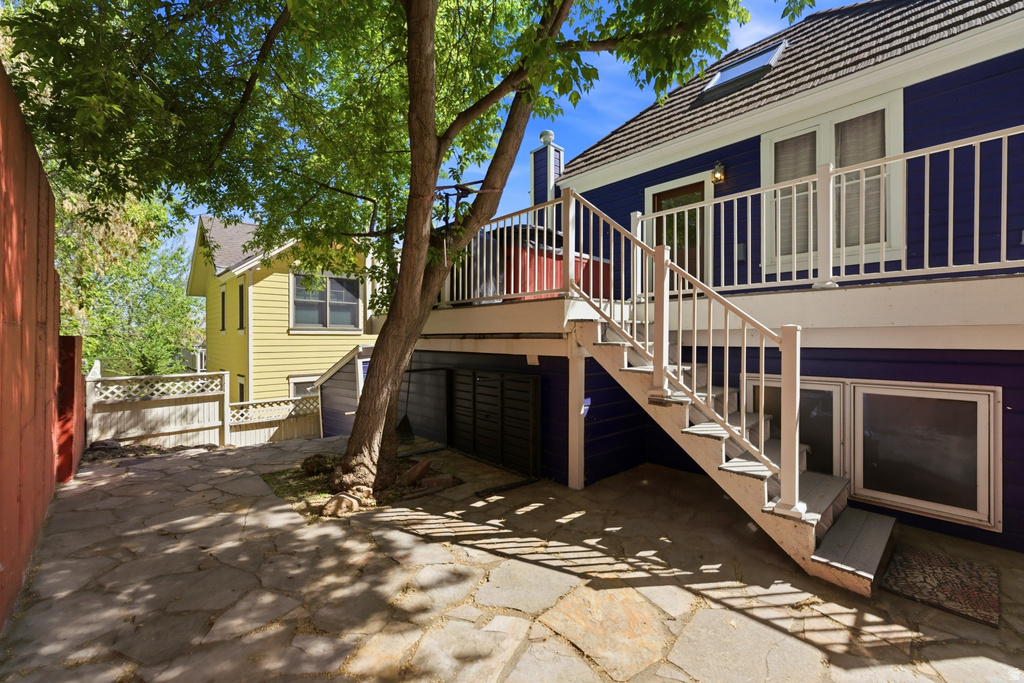 Stone patio featuring a multi-level deck with white railings and exterior stairs