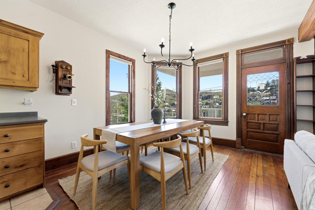 Dining area featuring wood-finish flooring, a chandelier, and multiple windows with wood-trimmed casings