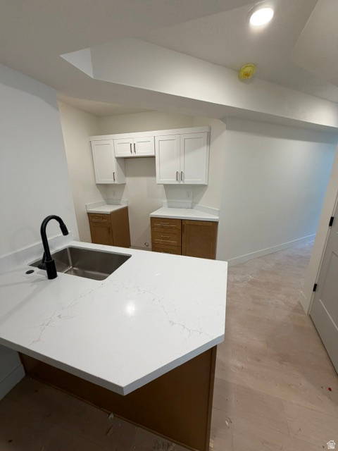 Kitchen island featuring a stainless steel sink with a matte black faucet, white quartz countertop with subtle veining, and wood-finish cabinetry