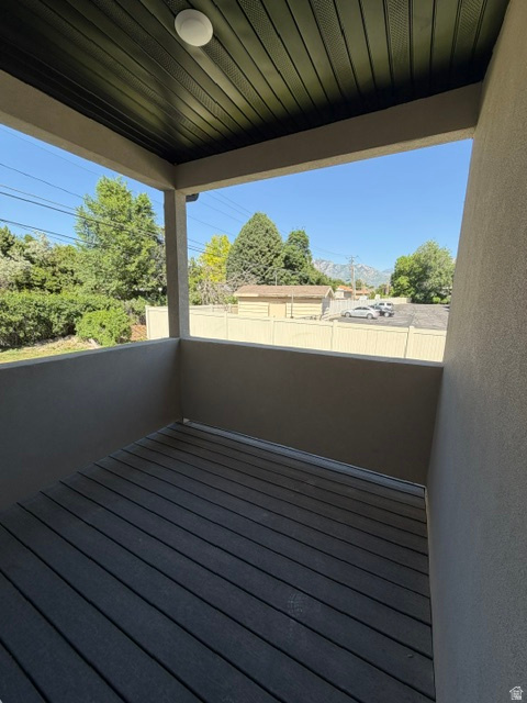 Private balcony featuring dark wood-finish decking and a textured stucco exterior