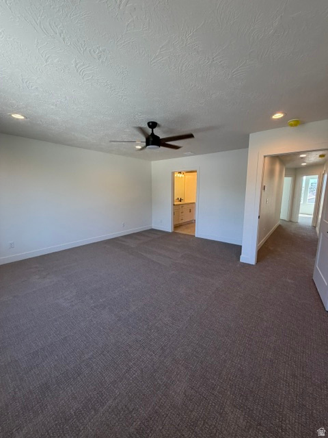 Spacious carpeted room featuring a ceiling fan, recessed lighting, and a neutral color palette