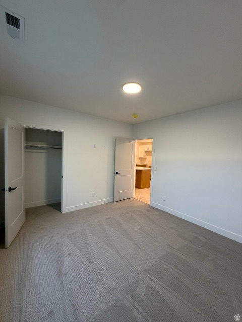 Carpeted room featuring a ceiling-mounted light fixture, white walls, and white baseboards