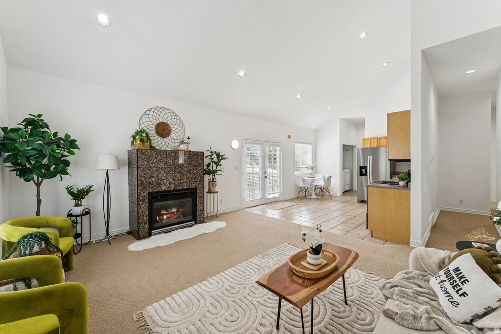 Living room featuring light carpet, a fireplace, light tile patterned flooring, lofted ceiling, and recessed lighting