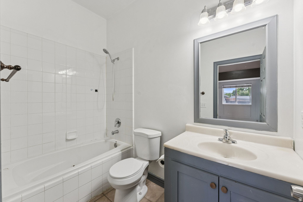 Bathroom with vanity, tiled shower / bath, and tile patterned flooring