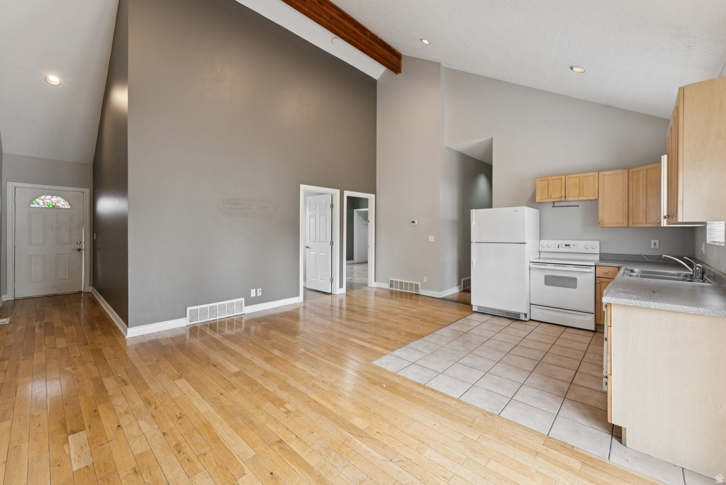 Kitchen featuring white appliances, recessed lighting, light wood finish cabinetry, light wood-style flooring, and light countertops